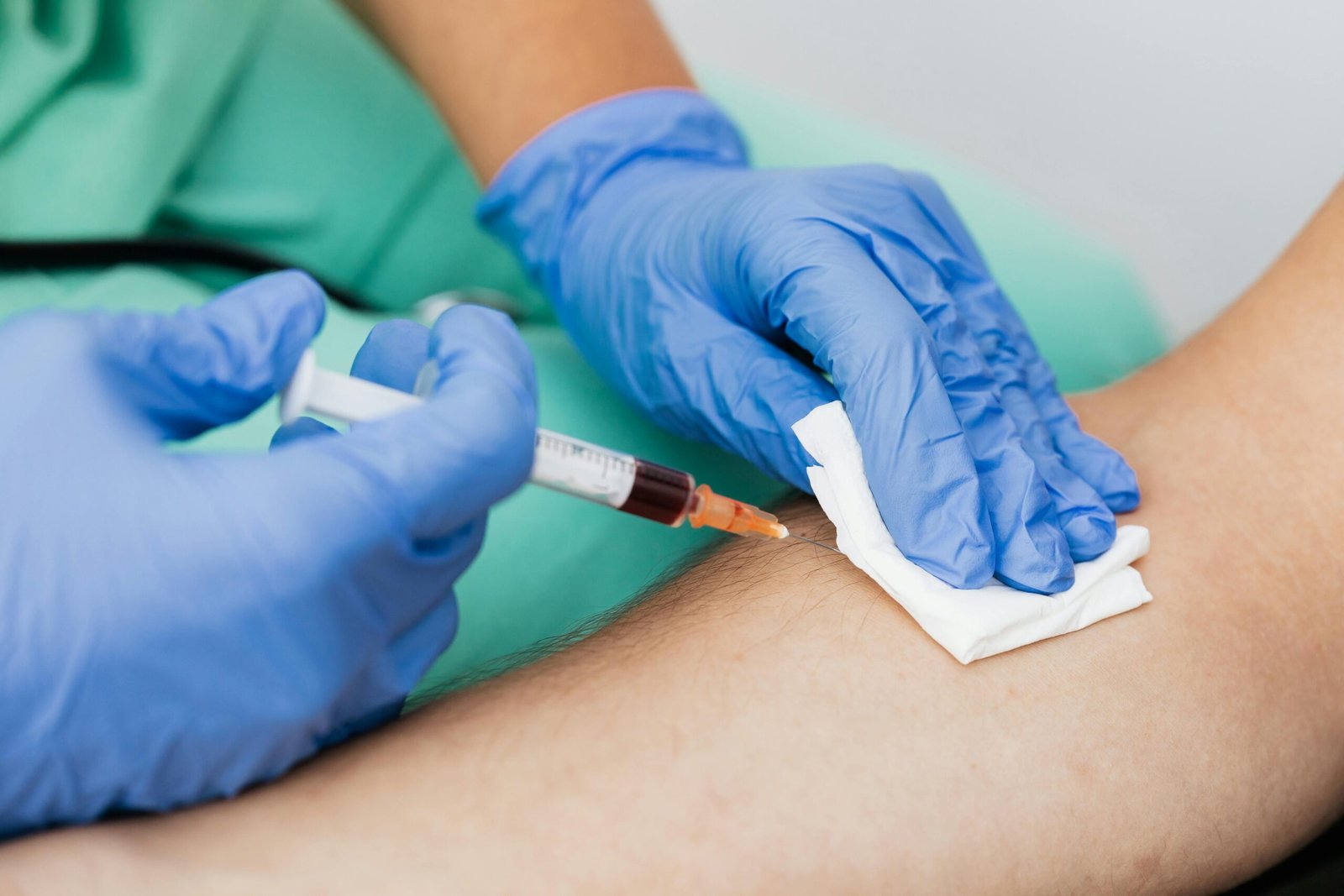 Close-up of a healthcare professional drawing blood with a syringe in a clinical setting.